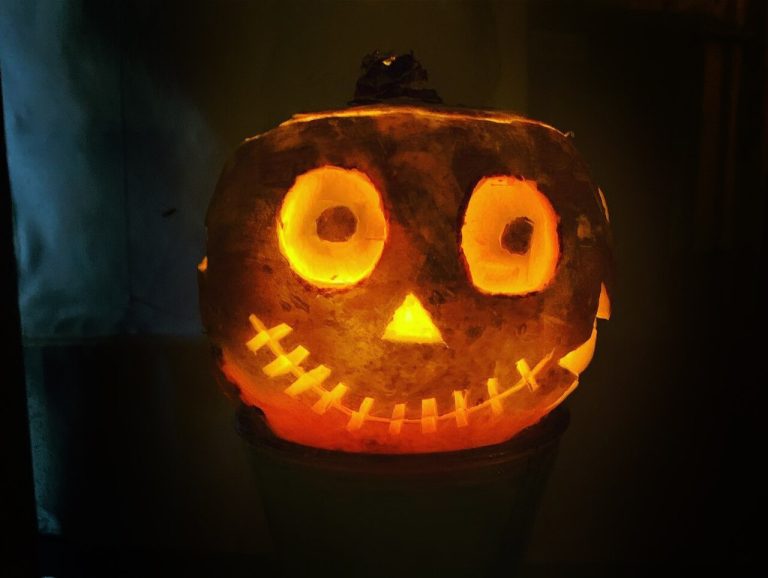 A carved turnip lantern glowing in the dark with round eyes and a jagged grin
